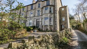A stone building with multiple windows and a stone wall in front. - Crow's Nest (Carnforth)