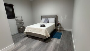 A bedroom with a bed, a nightstand, a ladder, and a blue rug. - Cozy studio just 5 min. Away from Coachella fest (Coachella)