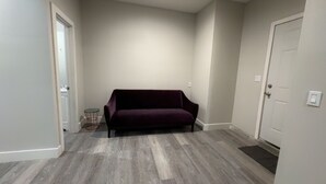 A room with a dark-colored sofa, a small round table, and a door. - Cozy studio just 5 min. Away from Coachella fest (Coachella)