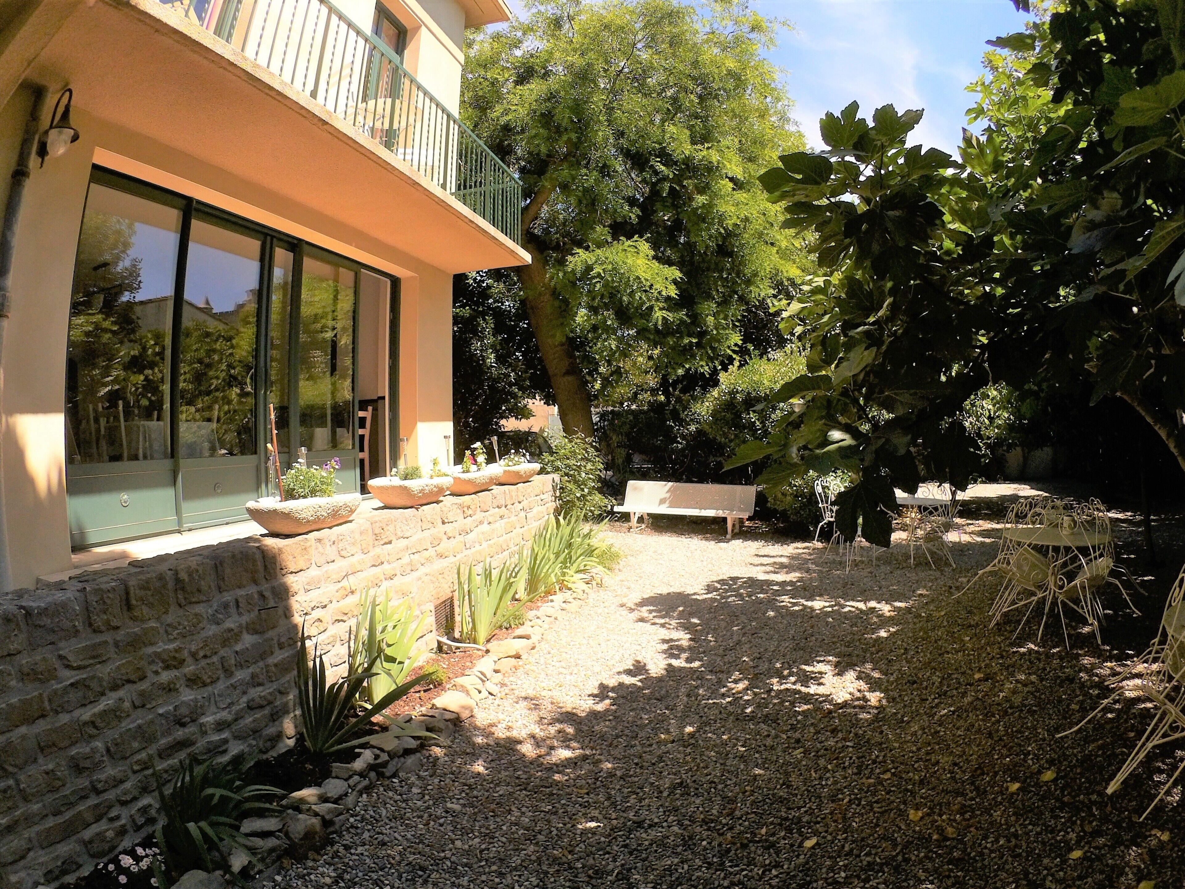 A courtyard with a gravel path, a bench, and potted plants.