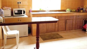Una cocina con una mesa de madera, un microondas, un fregadero y armarios de madera.