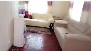 Una sala de estar con un sofá blanco, una mesita pequeña y una alfombra.
