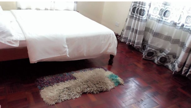Un dormitorio con una cama, un tapete estampado y un ventanal con cortinas.