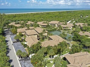 A resort with multiple bungalow-style buildings, a tennis court, and a beach view. - Blind Pass D204 (Sanibel)