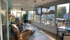 A sunlit room with a large window, a television, a sofa, a table, and a chair. - SPECIAL DEAL! WATERFRONT•King & Queen Suites•3 Baths•Kayaks,SUP•Manatee,Dolphin (Weeki Wachee)