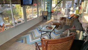 A sunlit room with a large window, a television, a dining table, and a sofa. - SPECIAL DEAL! WATERFRONT•King & Queen Suites•3 Baths•Kayaks,SUP•Manatee,Dolphin (Weeki Wachee)