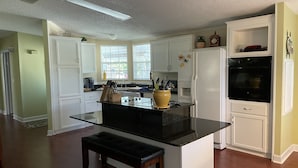 A kitchen with white cabinets, a black countertop, and a built-in oven. - SPECIAL DEAL! WATERFRONT•King & Queen Suites•3 Baths•Kayaks,SUP•Manatee,Dolphin (Weeki Wachee)