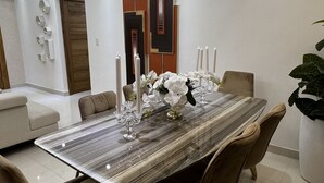 Un espace repas moderne avec une table en marbre, des chaises rembourrées et un panneau décoratif mural.