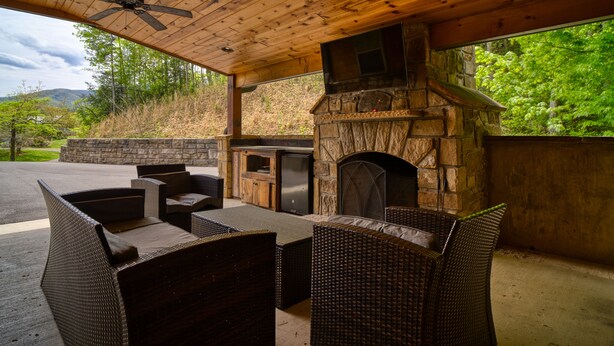 Un patio al aire libre con mobiliario de mimbre, una chimenea de piedra y un horno de piedra.