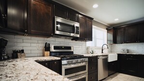 Una cocina moderna con armarios de madera oscura, electrodomésticos de acero inoxidable y un salpicadero de azulejos blancos.