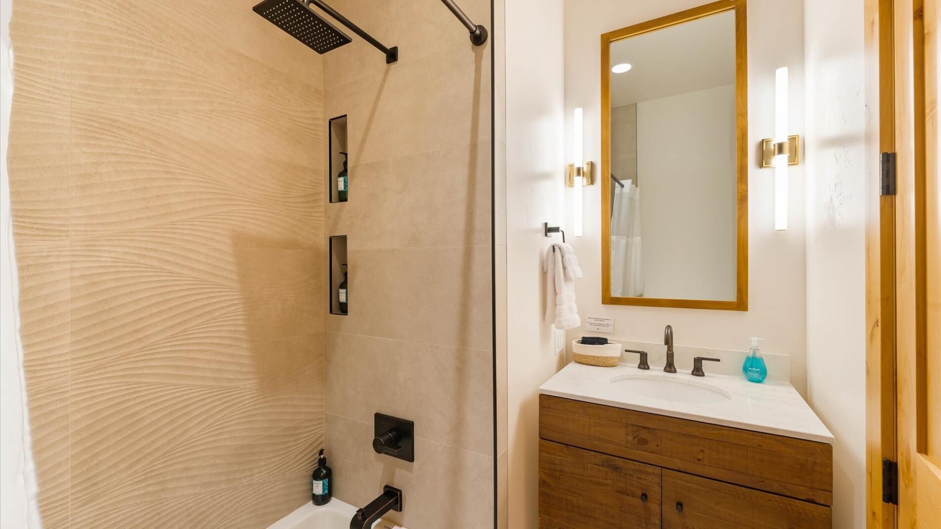 Un baño moderno con ducha, tocador y espejo.