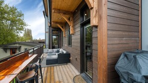 A wooden deck with outdoor seating, a barbecue grill, and a glass door leading to an interior space. - New Listing/Brand New Construction in the Heart of Downtown Whitefish (Whitefish)