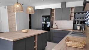 Eine moderne Küche mit dunklen Schränken, einer Holzecke und Pendelleuchten.