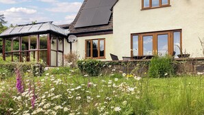 Une maison dotée d’un grand jardin, d’une véranda et d’un toit en pente.