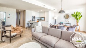 A modern living room with a sofa, a dining area with a table and chairs, and a kitchen in the background. - Blue View | sea view - garden - pool (Mijas Costa)