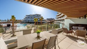 Eine Dachterrasse mit Pool, Sitzgelegenheiten im Freien und Blick auf einen modernen Gebäudekomplex.