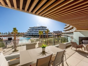 Eine Dachterrasse mit Pool, Sitzgelegenheiten im Freien und Blick auf einen modernen Gebäudekomplex.