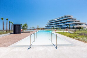 Um hotel moderno com piscina, área de estar ao ar livre e vista clara para o mar.