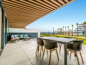 An outdoor patio with a table and chairs, a sofa, and a view of the sea and buildings. - Fari | Beach - terrace - pool (Torremolinos)