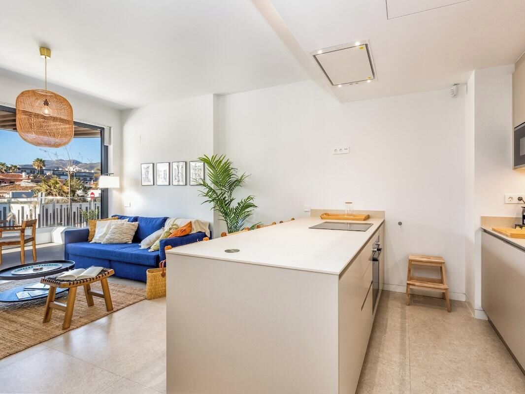 Een moderne woonruimte met een bank, salontafel en een klein keukenhoekje met een aanrecht en spoelbak.