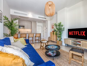 A modern living room with a sofa, coffee table, and TV displaying 'NETFLIX'.