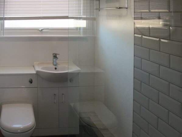 Ein Badezimmer mit Toilette, Waschbecken und Duschbereich.