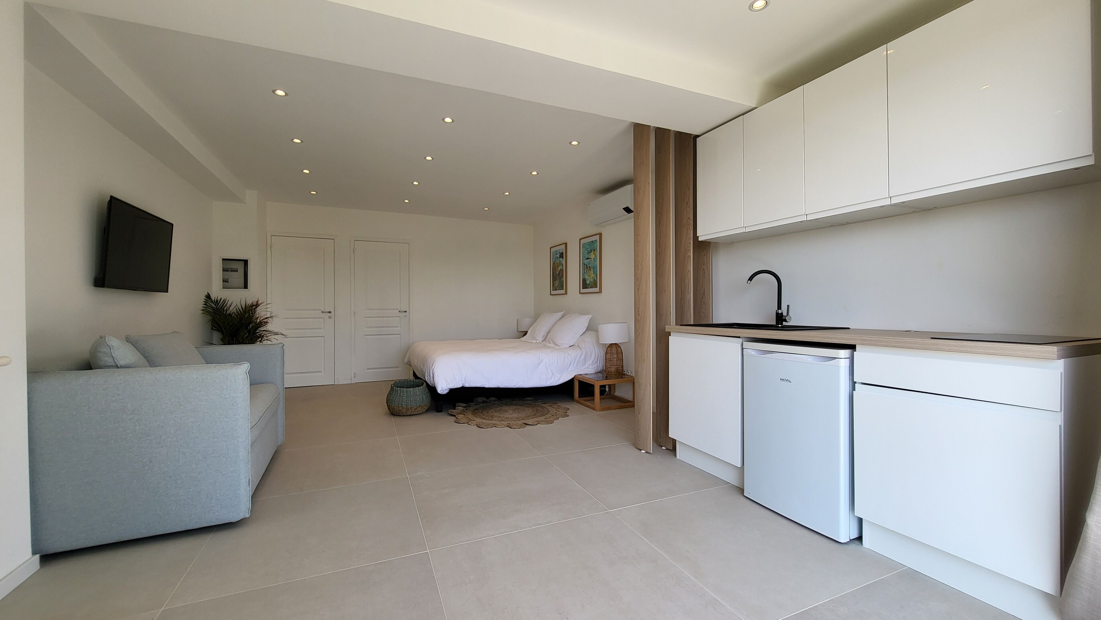 Un apartamento moderno con kitchenette, cama, sofá y televisor de pantalla plana.