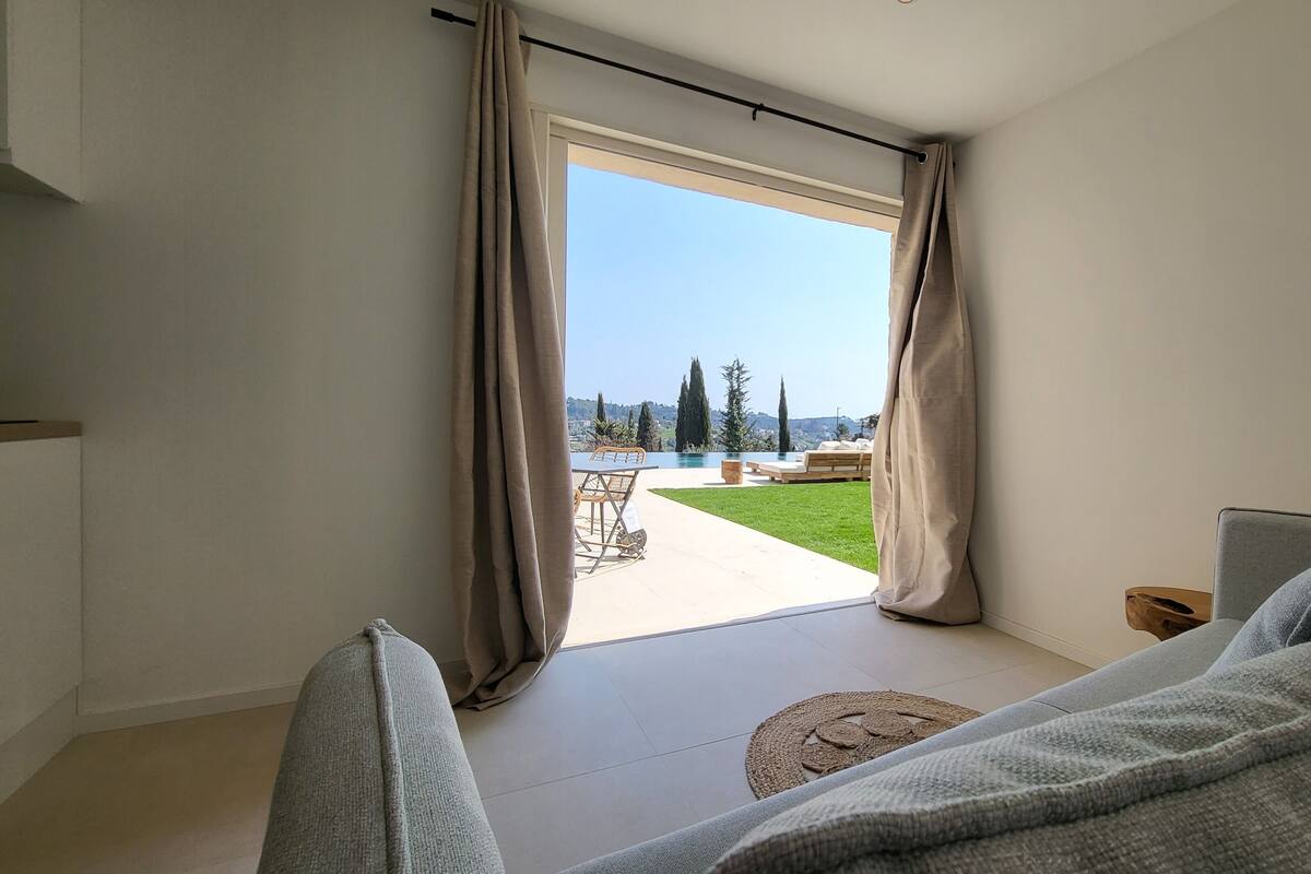 A modern living room with a large sliding glass door leading to a pool and outdoor seating area.