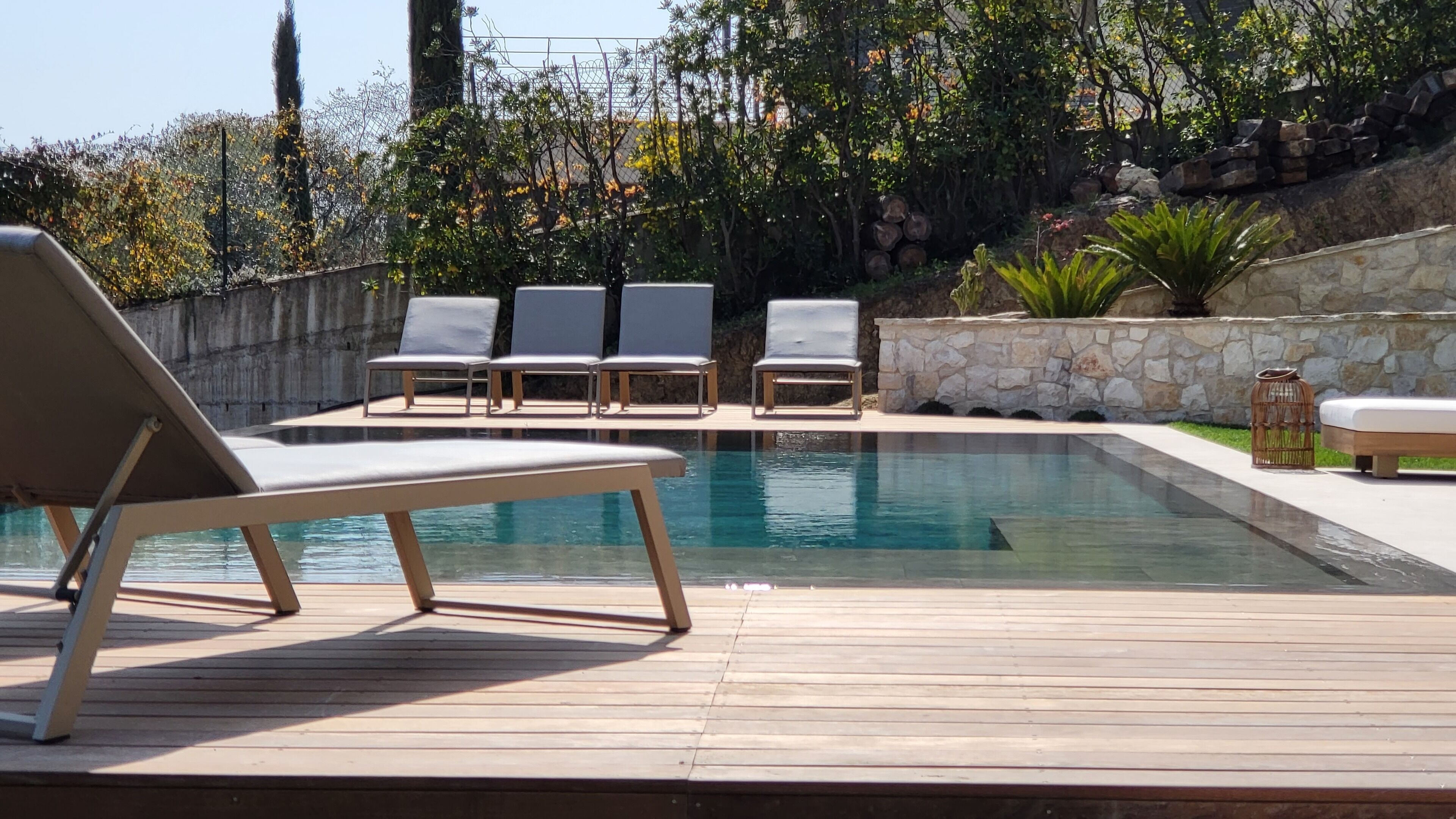 A swimming pool with lounge chairs and a stone wall.