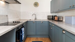 A compact kitchen with a sink, stove, and microwave. - Calon Y Mor - Close to Village and Beach (Saundersfoot)