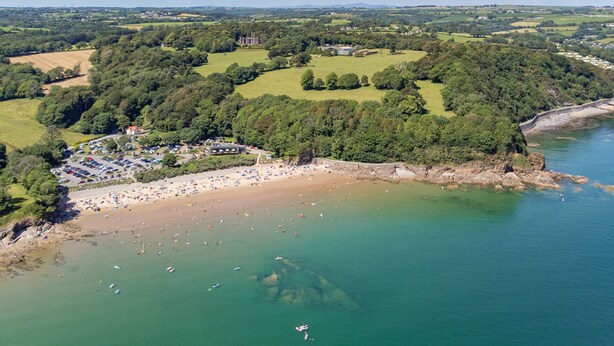 An aerial view of a coastal area with a beach, parking lot, and a large building surrounded by greenery. - Calon Y Mor - Close to Village and Beach (Saundersfoot)