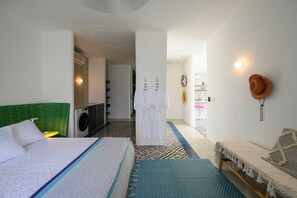 A hotel room with a bed, a washing machine, a robe, and a hat on the wall. - Casa Dos Aguas: Yelapa Beachfront 1BR with Bay Views & Open-Air Terrace (Yelapa)