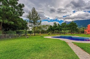 Surrounded by lush greenery, this outdoor space features a swimming pool and a beautifully manicured lawn.
