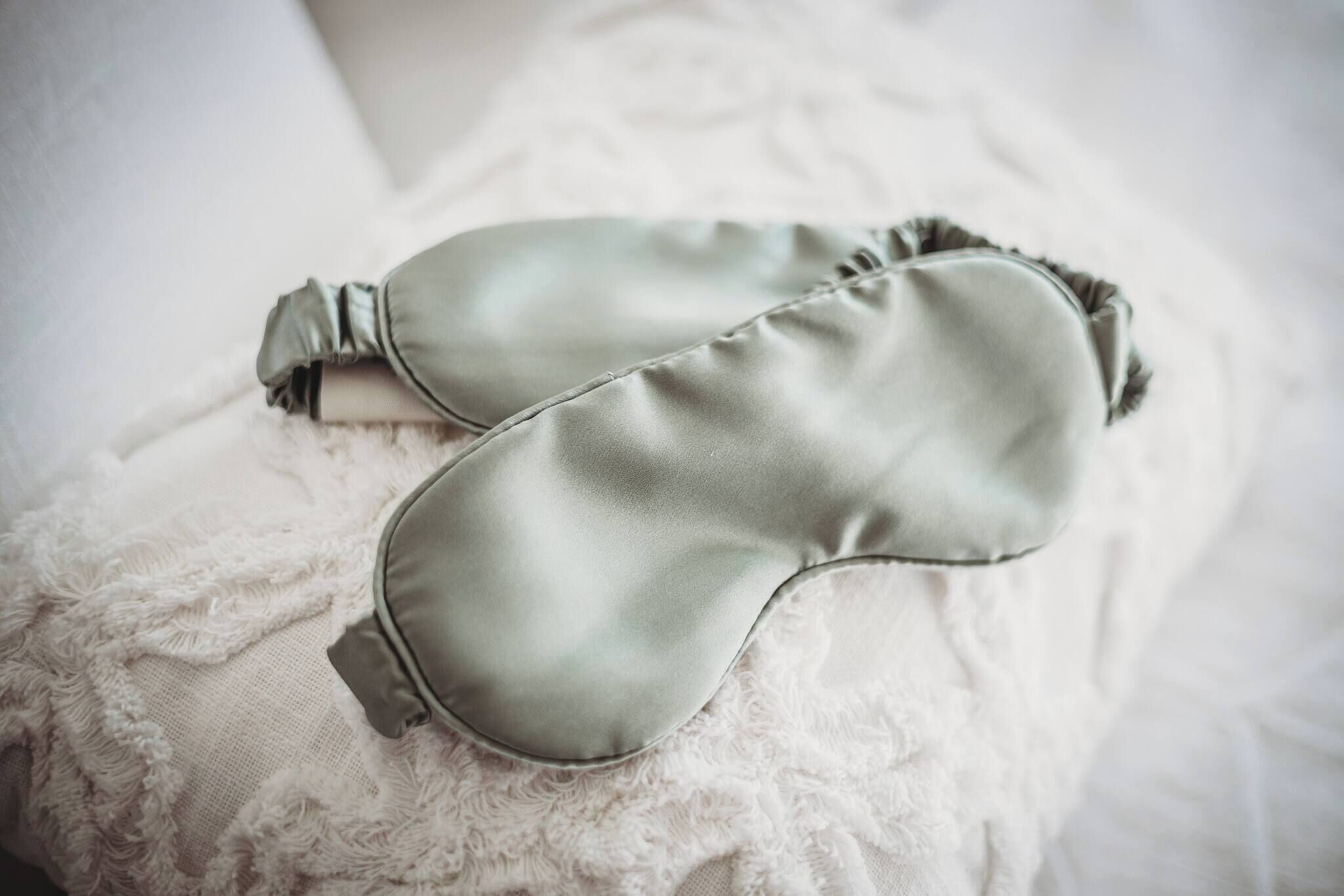 A pair of green eye masks on a white textured pillow.