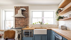 A kitchen with a brick wall, a stove, oven, microwave, and a window with a view.
