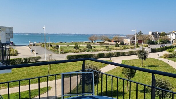 Vista costera desde un balcón, con un camino despejado que lleva al mar, un césped bien cuidado y un edificio con la leyenda 'Thalasso Concarneau'.