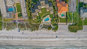 Vista aérea de una propiedad costera con piscina, cancha de tenis y zona de playa.