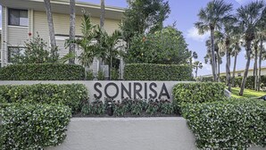 Letrero con la palabra "SONRISA" rodeada de follaje y palmeras.