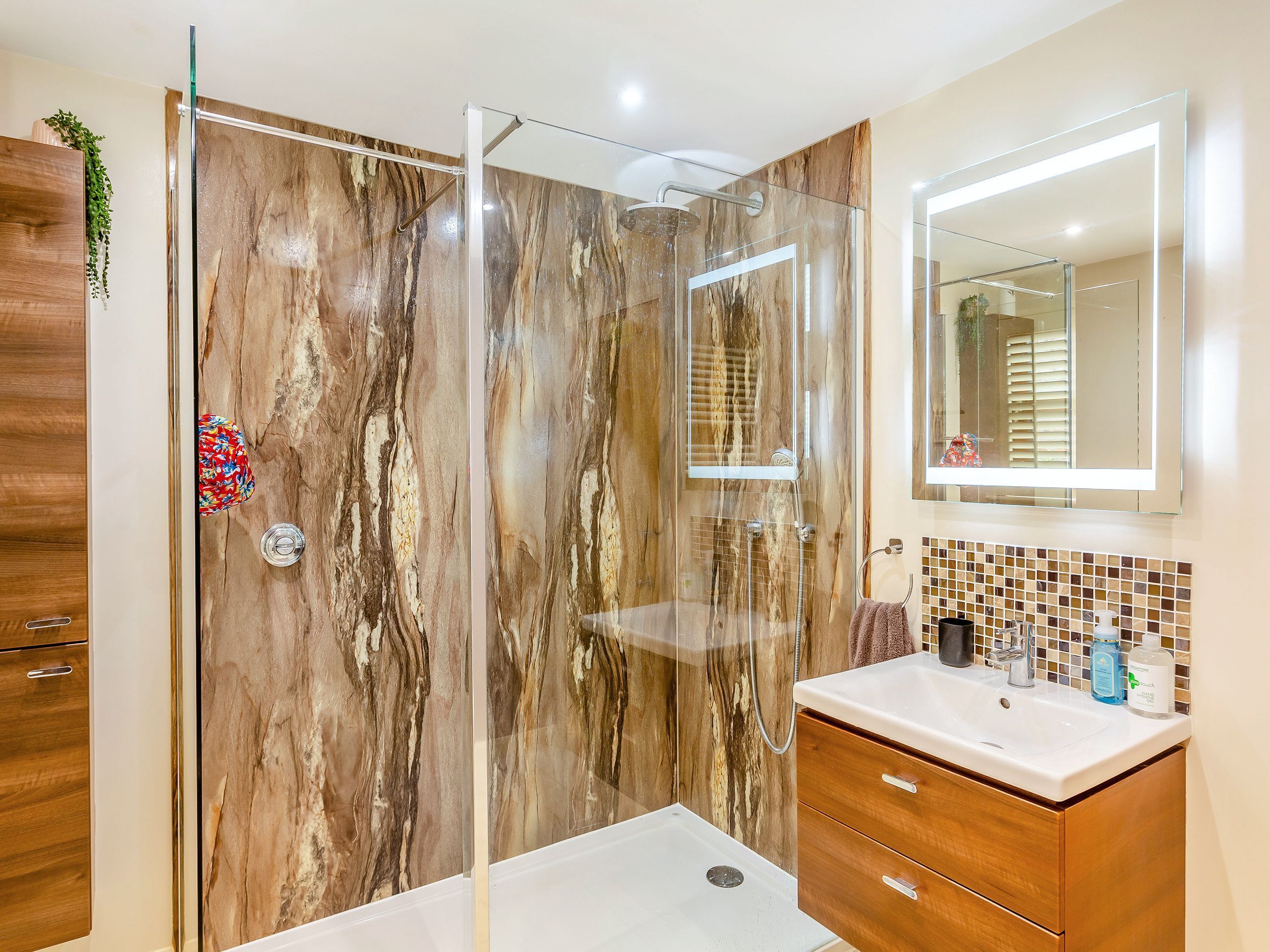 A modern bathroom with a glass-enclosed shower, a wooden vanity, and a large mirror.