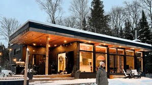 Una casa moderna con porche cubierto y amplias ventanas, rodeada de nieve.