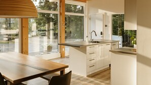 Una cocina moderna con techo de madera, ventanas amplias y una isla central con pileta.
