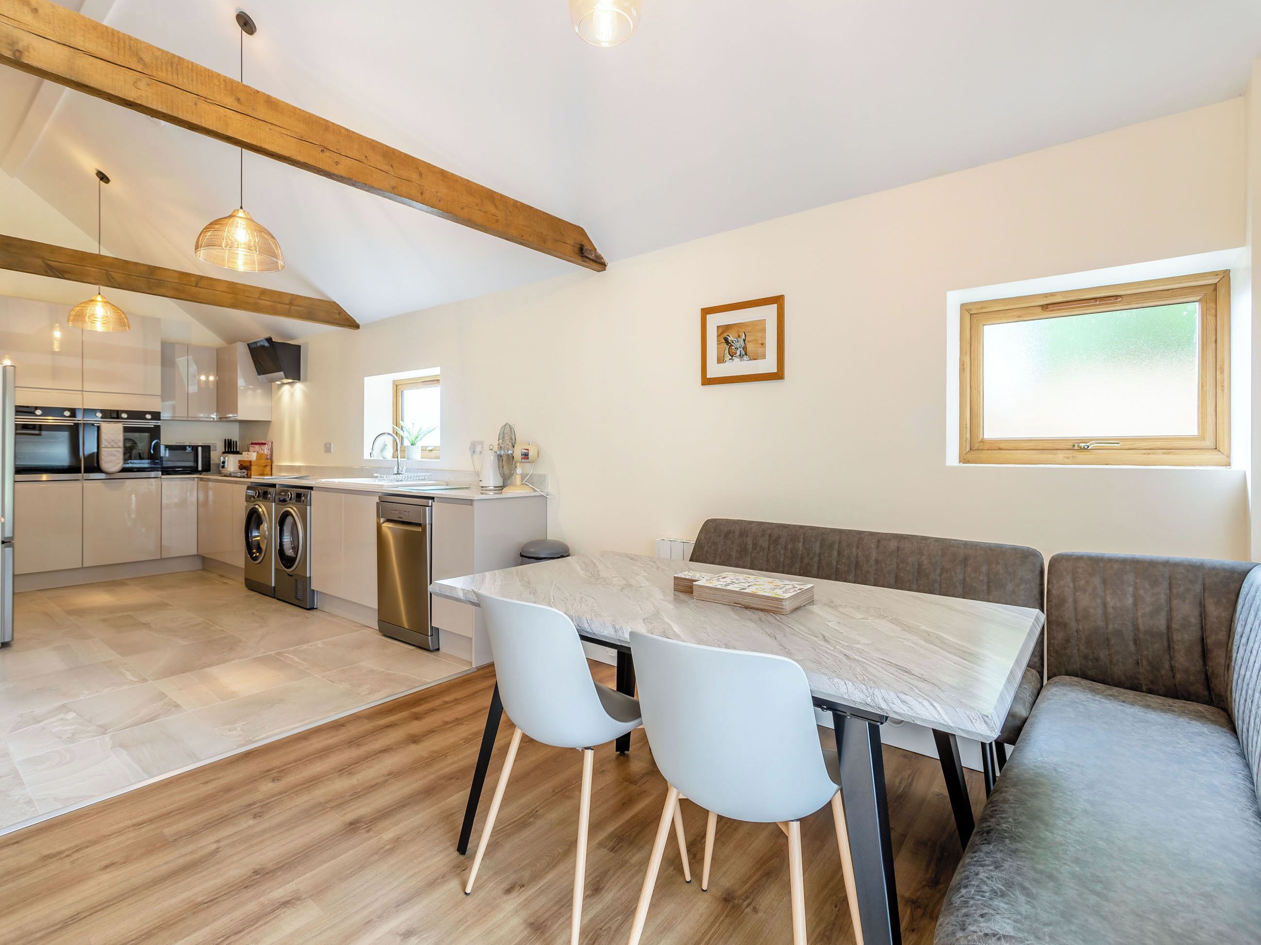 Et moderne køkken med indbyggede apparater, et spiseområde med et marmorbord og et stort vindue.