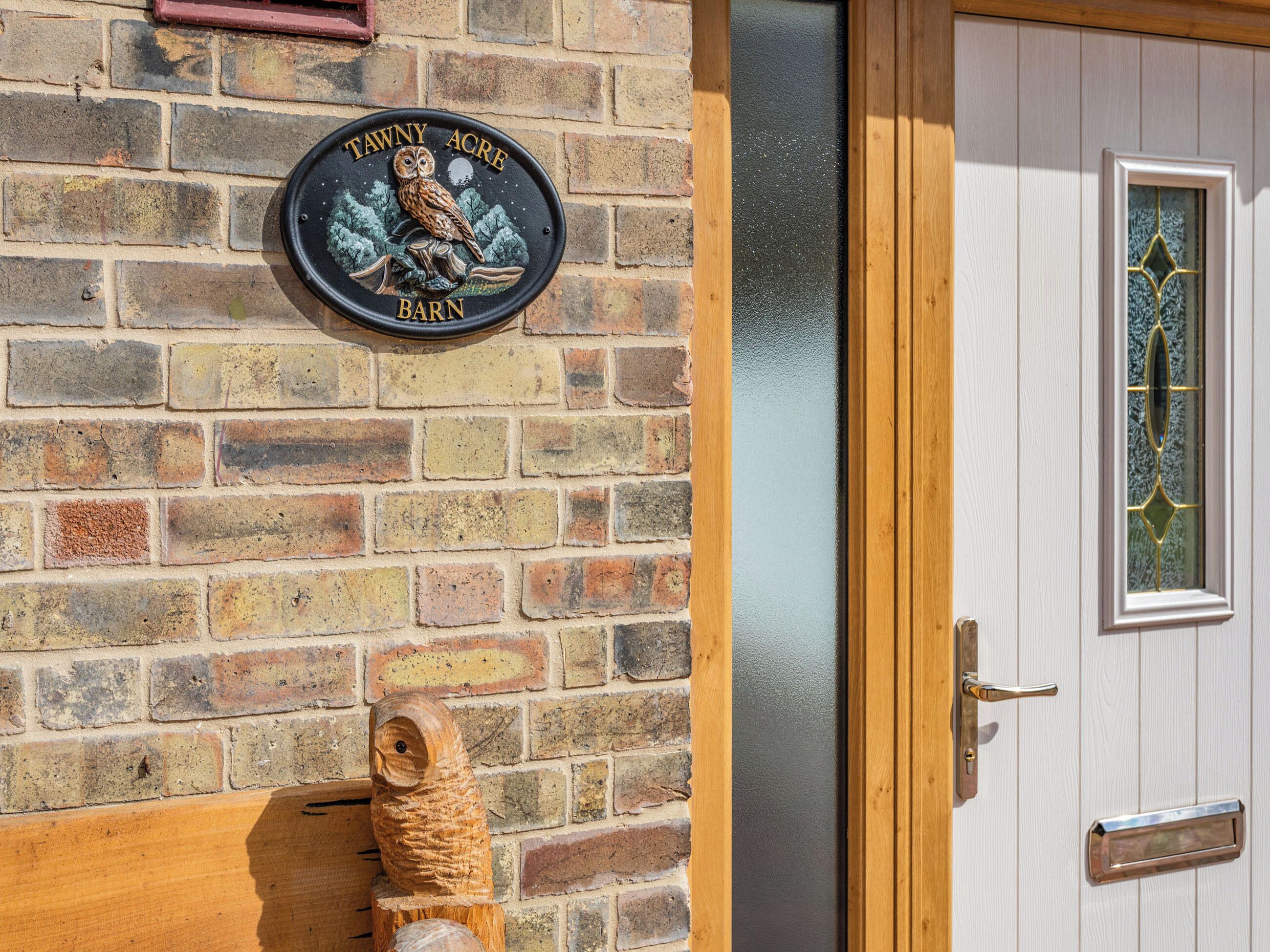 A brick wall with a sign reading 'Tawny Acre Barn' and a wooden owl decoration.