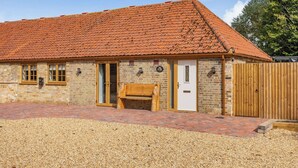 A building with a red-tiled roof, brick walls, a wooden bench, and a gravel driveway. - Tawny Acre Barn - UK38614 (South Walton Highway, Wisbech)