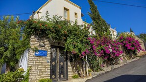 Un bâtiment en pierre avec une porte noire et une enseigne indiquant « AEGEAN GATE ».