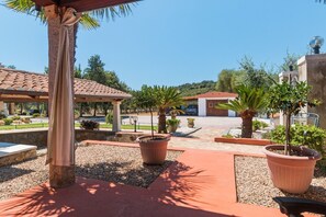 Ein Innenhof mit einer Pergola, Blumentöpfen und einem Gebäude im Hintergrund.
