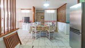 Un coin repas avec une table dressée pour quatre personnes, un téléviseur et un réfrigérateur.