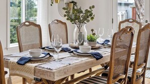 Een eettafel met stoelen, een vaas met planten en een decoratief wandobject.