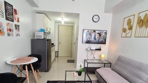 Ein gemütlicher Wohnbereich mit Sofa, kleinem Tisch, Fernseher und Küchenzeile.