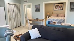 A hotel room with a bed, a desk, a chair, a sofa, and a small table.